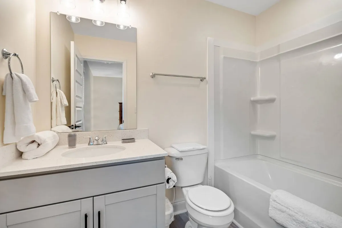 A bright and refreshing bathroom with a vanity, sink, mirror, and bathtub. The scene suggests opportunities for both personal grooming and indulgent relaxation, such as a soothing bath after a workout or swim.