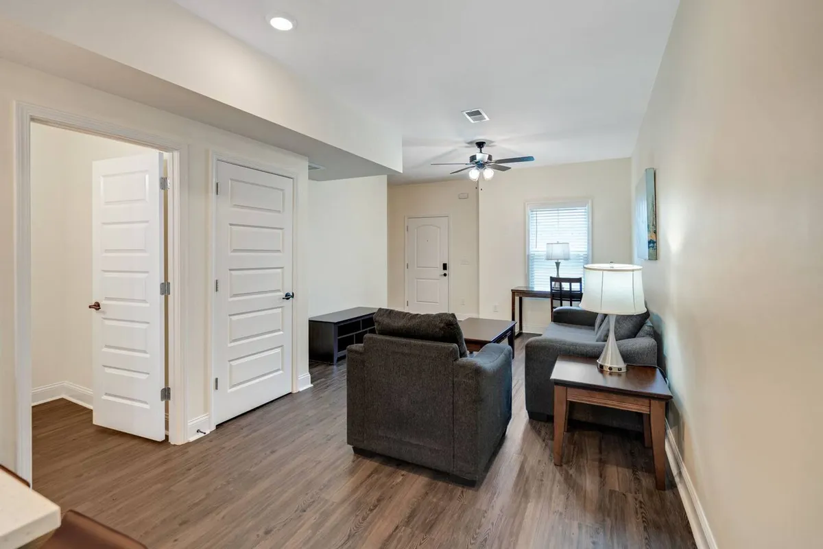 A welcoming interior showing a cozy sofa, a table lamp, and a dining table. The open layout connects the living and dining areas, conveying a sense of effortless flow and communal space.