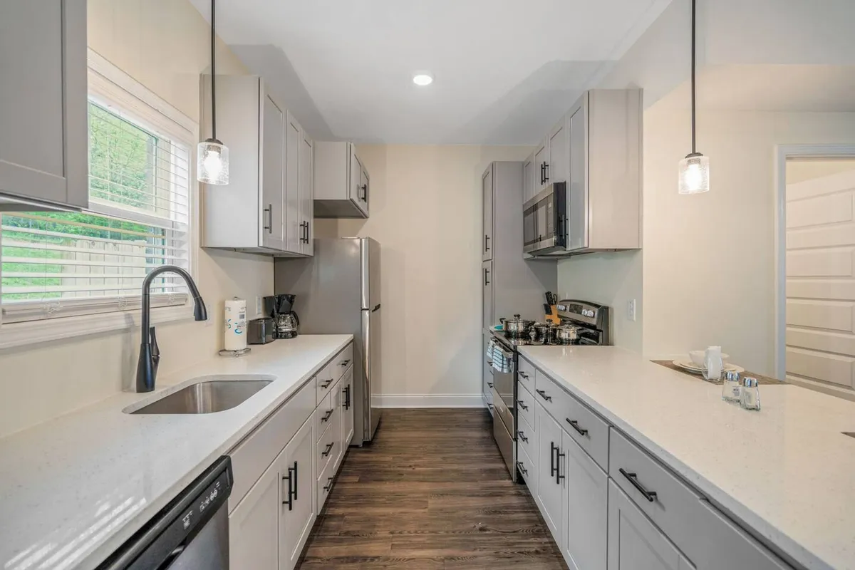 A spacious and inviting kitchen features a large countertop, stainless steel appliances, a sleek sink, and a central kitchen island. The open layout suggests ample room for cooking and entertaining, while subtle decorative touches add to the warmth and functionality of the space.