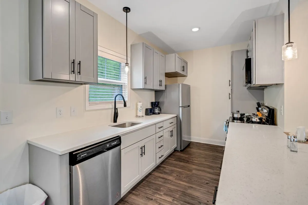 A modern kitchen area showcasing sleek cabinetry, a spacious countertop, integrated sink, and up-to-date appliances. The design is both functional and stylish, hinting at comfort and sociability for cooking or sharing meals.