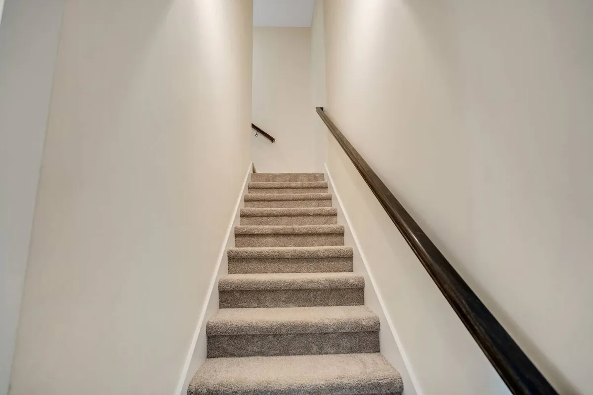 This image features a welcoming staircase with a stylish handrail, suggesting an inviting transition between different spaces within the home. The image hints at the excitement of exploring the property, evoking feelings of anticipation as guests move to discover what lies beyond.